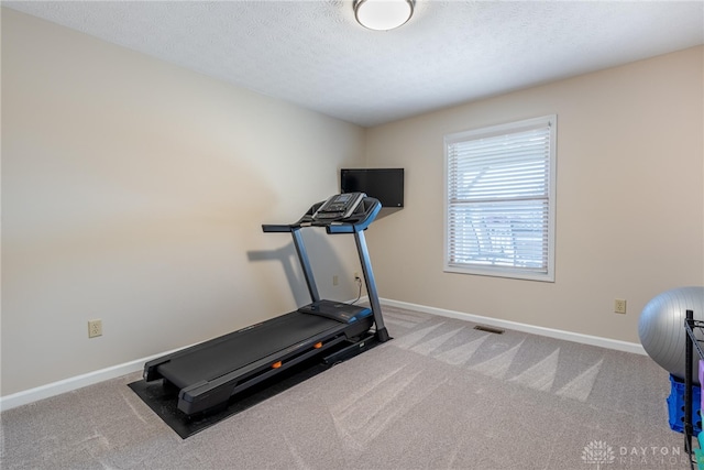 workout room with light carpet, visible vents, baseboards, and a textured ceiling