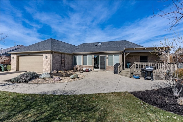 back of property featuring driveway, a shingled roof, an attached garage, a yard, and brick siding