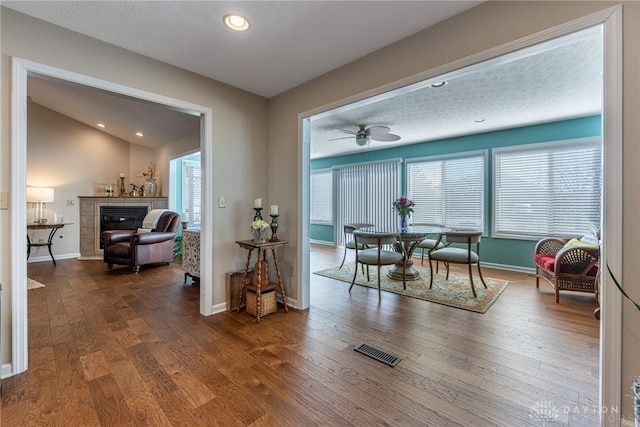 dining space featuring baseboards, visible vents, wood finished floors, a fireplace, and recessed lighting