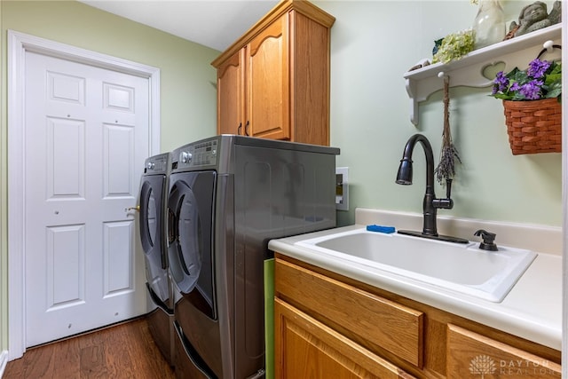 washroom featuring a sink, cabinet space, washing machine and dryer, and dark wood-type flooring