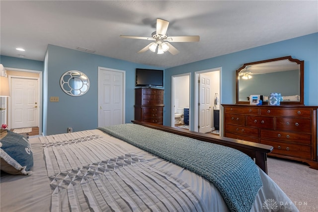 carpeted bedroom with ensuite bath, ceiling fan, and visible vents