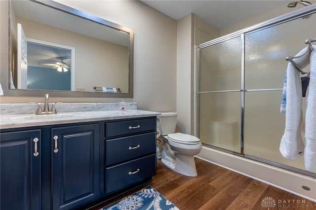 full bathroom with toilet, ceiling fan, wood finished floors, an enclosed shower, and vanity