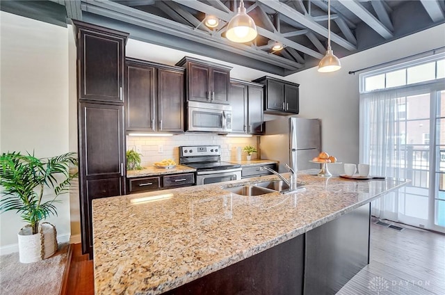 kitchen with decorative backsplash, appliances with stainless steel finishes, decorative light fixtures, dark brown cabinets, and a sink