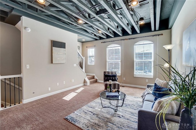 sitting room featuring carpet, baseboards, and stairs