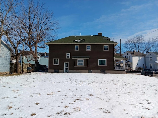 snow covered rear of property featuring a chimney