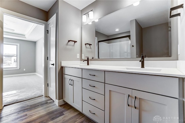 full bath featuring a sink, a shower stall, double vanity, and wood finished floors