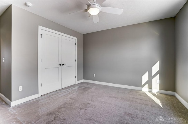 unfurnished bedroom featuring a closet, baseboards, a ceiling fan, and carpet floors