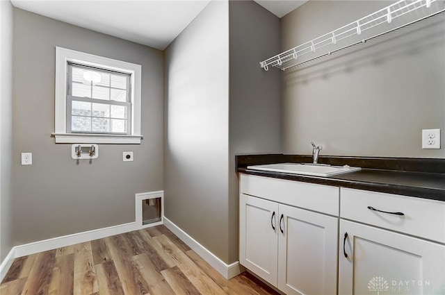 laundry room with hookup for an electric dryer, baseboards, light wood-type flooring, hookup for a washing machine, and a sink