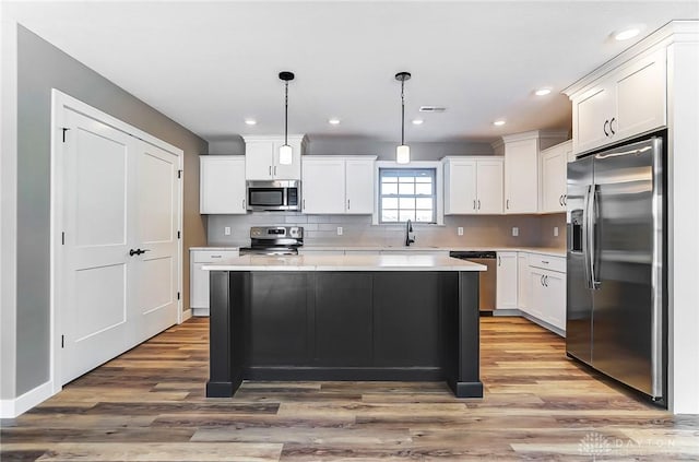 kitchen with a sink, light countertops, wood finished floors, and stainless steel appliances