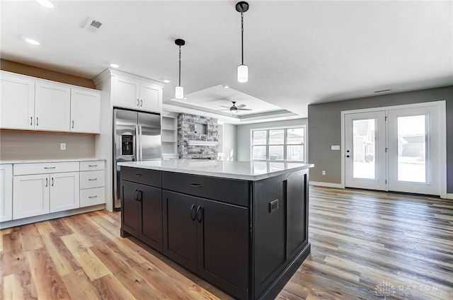 kitchen with a tray ceiling, light wood-type flooring, a ceiling fan, white cabinets, and light countertops