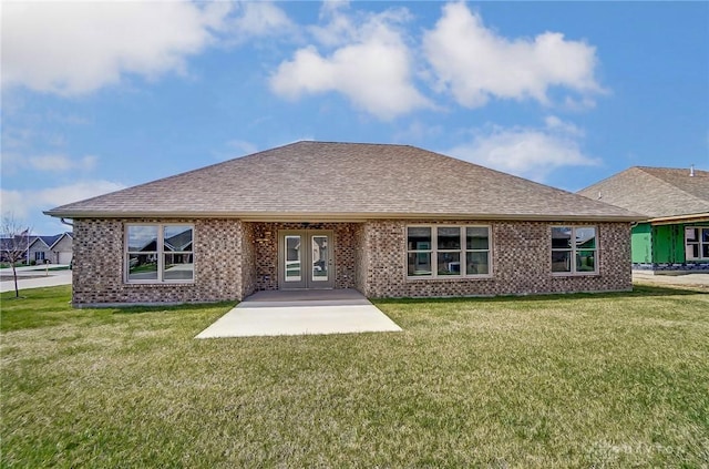 rear view of property featuring brick siding, french doors, a shingled roof, and a yard