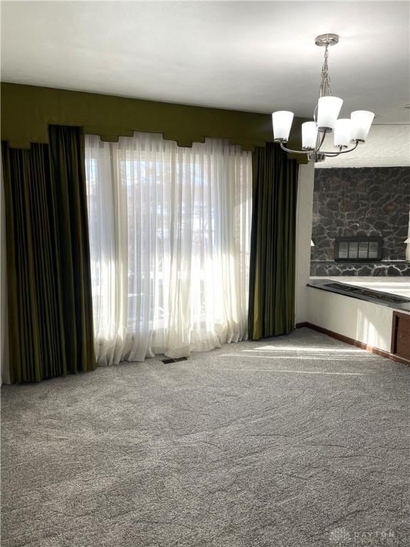 empty room with carpet and a notable chandelier