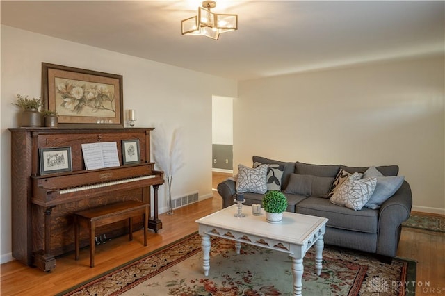 living room featuring baseboards, visible vents, and wood finished floors