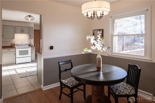 dining area featuring baseboards, light wood-type flooring, and an inviting chandelier