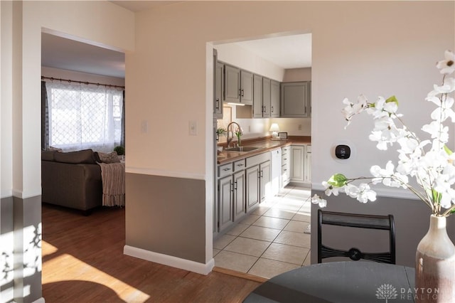 kitchen with light wood-style floors, baseboards, open floor plan, and a sink