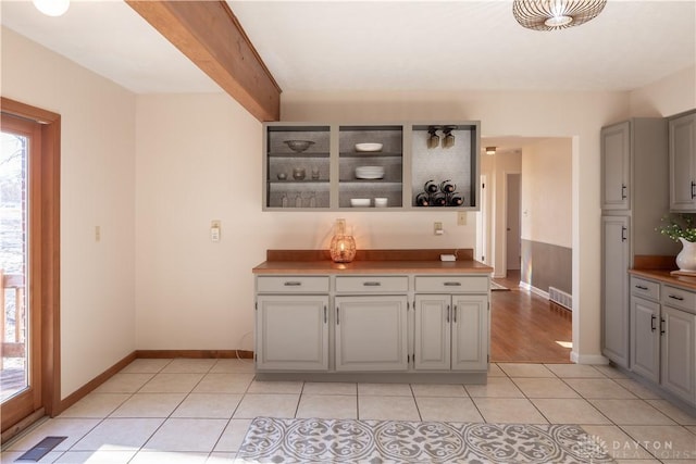 kitchen featuring light tile patterned floors, gray cabinets, visible vents, and open shelves