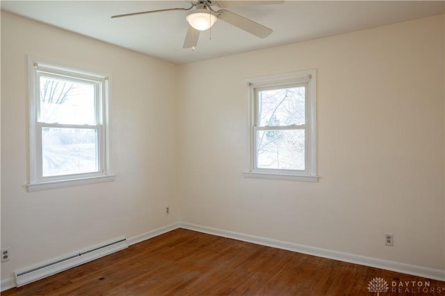 empty room with baseboard heating, plenty of natural light, wood finished floors, and baseboards