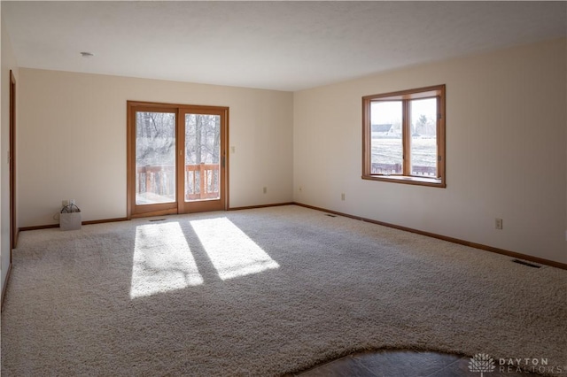 carpeted spare room with plenty of natural light, visible vents, and baseboards