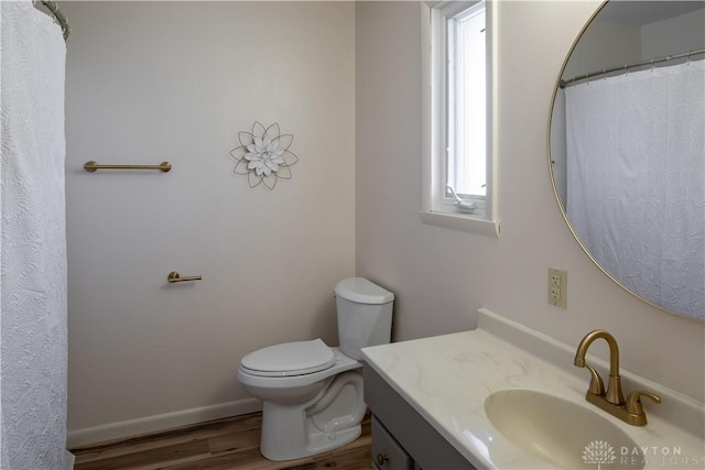 bathroom featuring baseboards, vanity, toilet, and wood finished floors