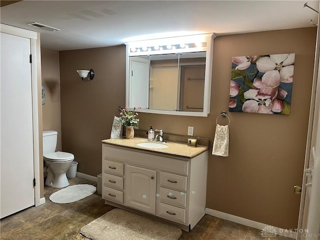 bathroom featuring toilet, vanity, visible vents, and baseboards