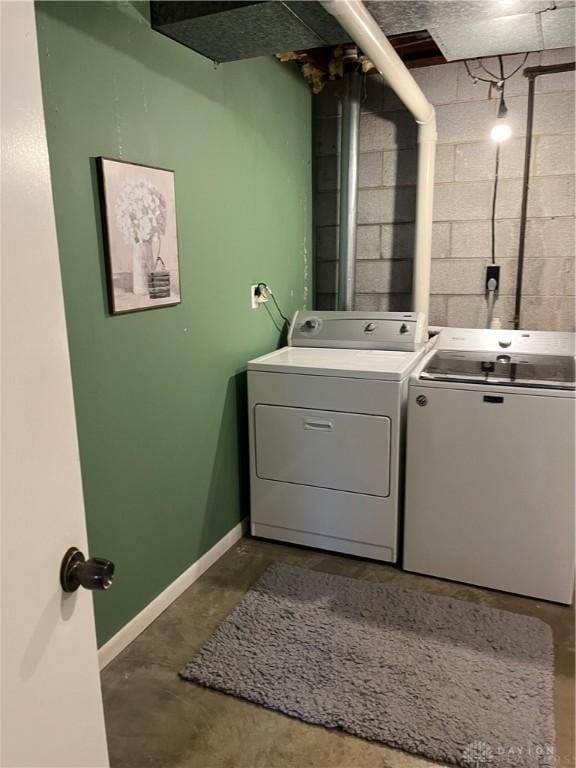 clothes washing area with laundry area, washing machine and dryer, concrete block wall, and baseboards