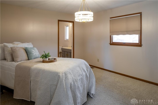 carpeted bedroom featuring ensuite bath, baseboards, and a chandelier