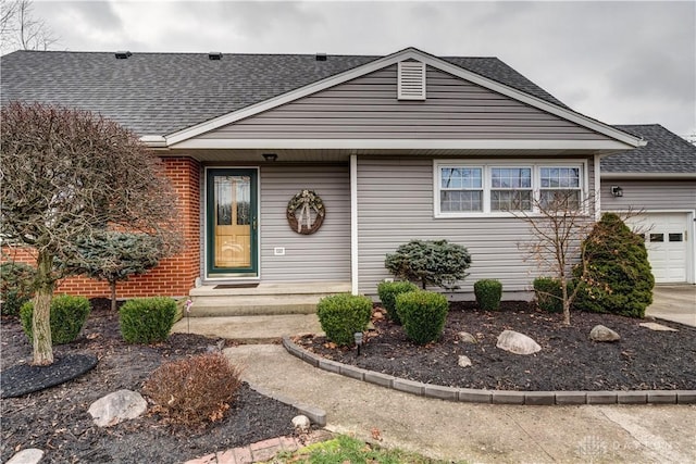 view of front of house featuring an attached garage, brick siding, and roof with shingles