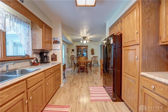 kitchen with light wood finished floors, ceiling fan, light countertops, freestanding refrigerator, and a sink