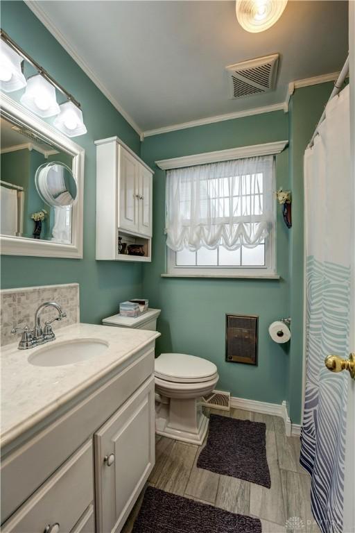 full bath featuring visible vents, vanity, crown molding, and toilet