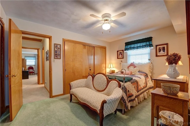 bedroom with a closet, baseboards, light colored carpet, and a ceiling fan