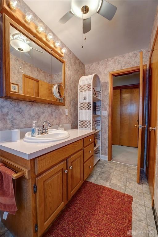 bathroom with wallpapered walls, vanity, and ceiling fan