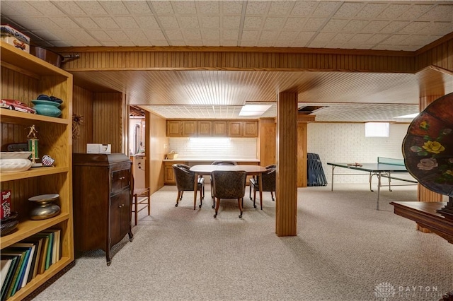 dining room featuring light colored carpet and wood walls