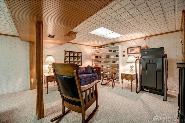 living area with visible vents, brick wall, and light carpet