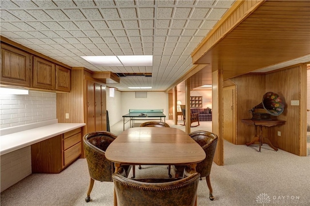 dining area with light colored carpet and wood walls