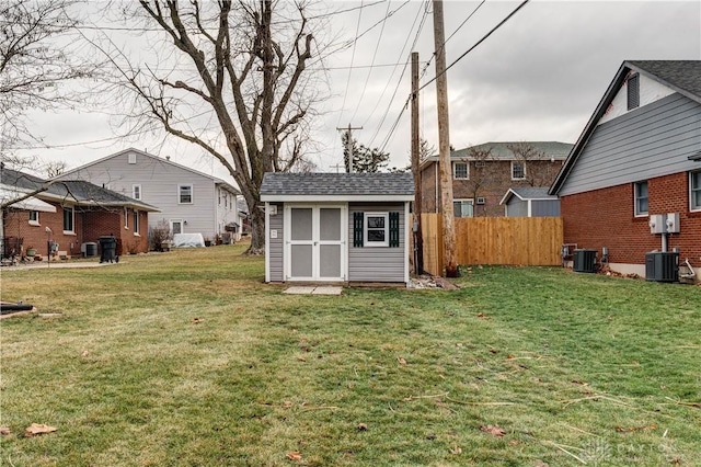 view of yard featuring a storage shed, central AC unit, an outdoor structure, and fence