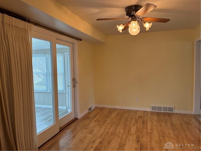 empty room with light wood finished floors, visible vents, a ceiling fan, and baseboards