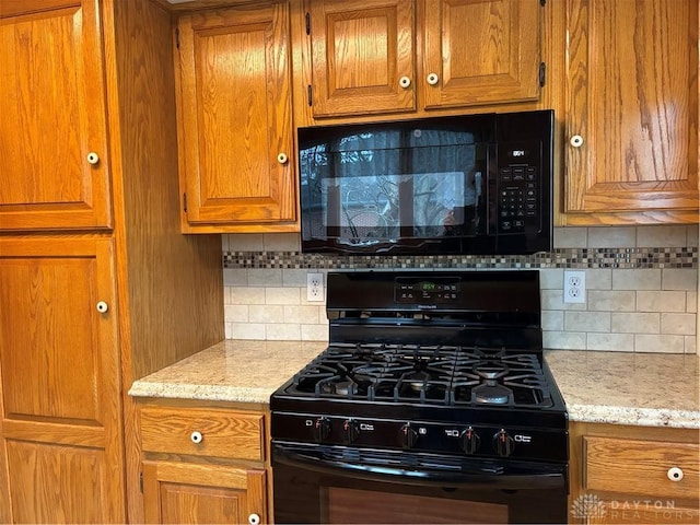 kitchen featuring black appliances, light stone counters, brown cabinetry, and backsplash