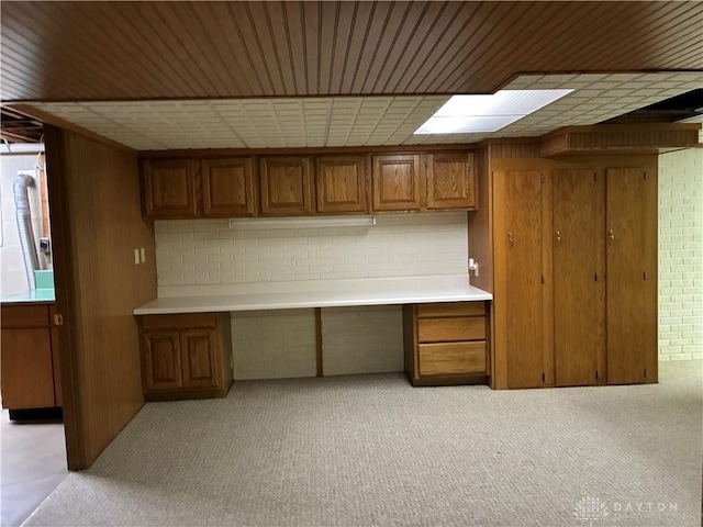 interior space featuring brown cabinetry, wooden walls, built in study area, and light countertops