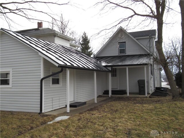 back of property featuring metal roof, a yard, and a standing seam roof