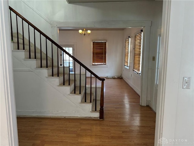 staircase with a notable chandelier and wood finished floors