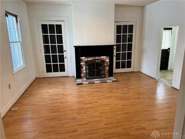 unfurnished living room featuring light wood-type flooring, a fireplace, and baseboards