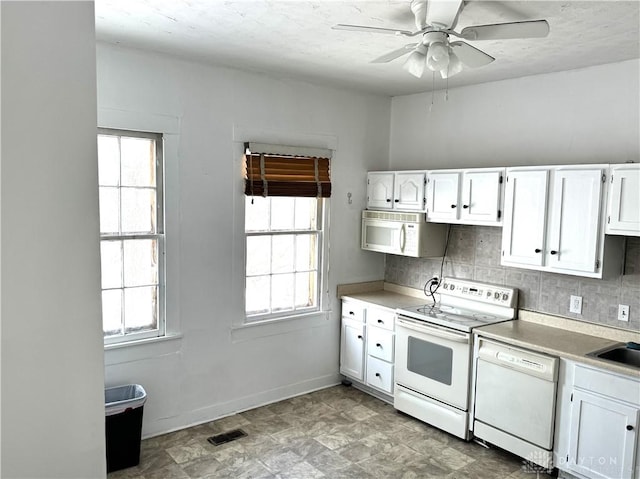 kitchen featuring white appliances, visible vents, white cabinets, light countertops, and plenty of natural light