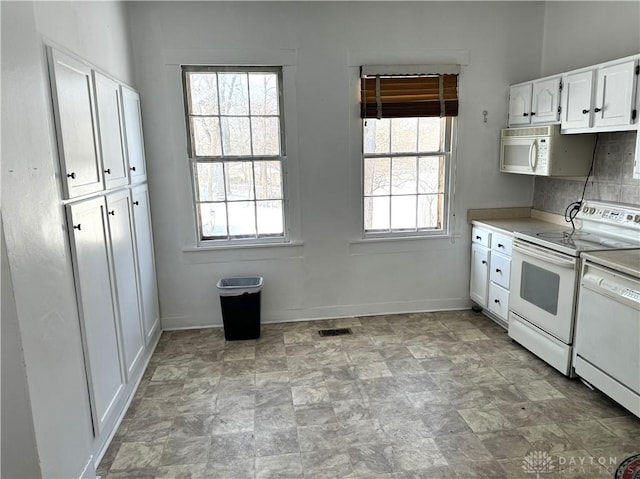 kitchen featuring light countertops, visible vents, white cabinets, white appliances, and baseboards