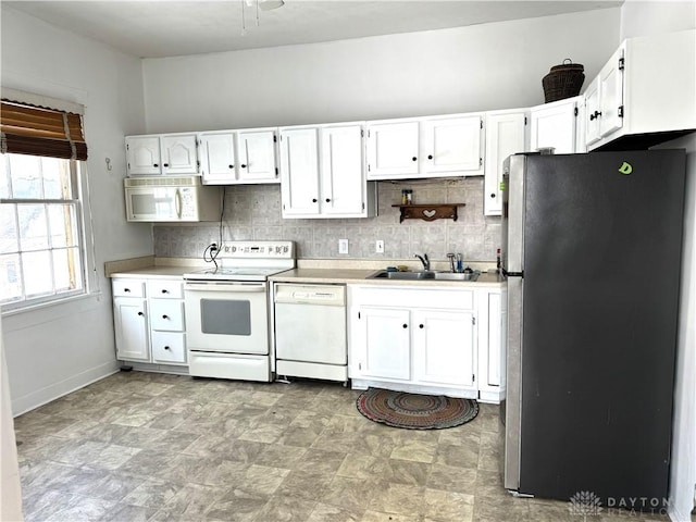 kitchen featuring white appliances, tasteful backsplash, light countertops, white cabinetry, and a sink