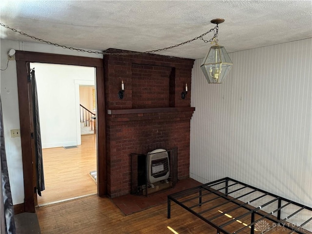 living room with heating unit, a textured ceiling, and wood finished floors