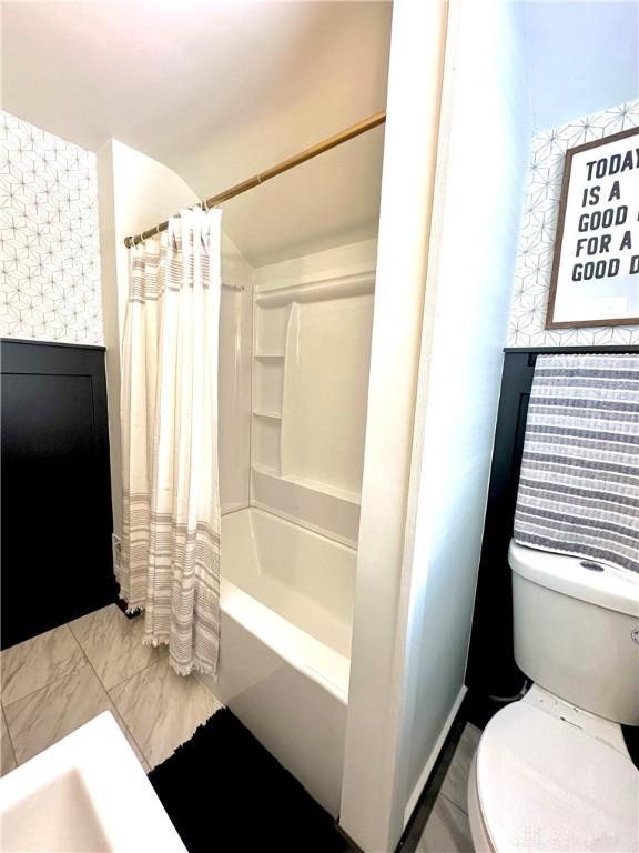 bathroom featuring toilet and shower / bath combo with shower curtain