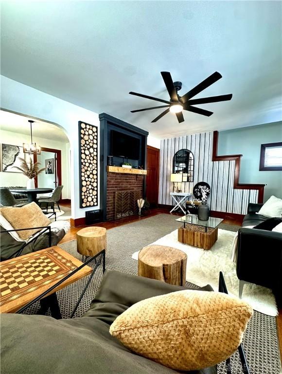 living room featuring a ceiling fan, arched walkways, and baseboards