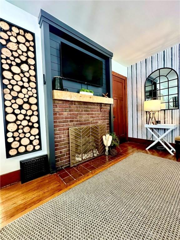 unfurnished living room featuring baseboards, visible vents, a fireplace, and wood finished floors