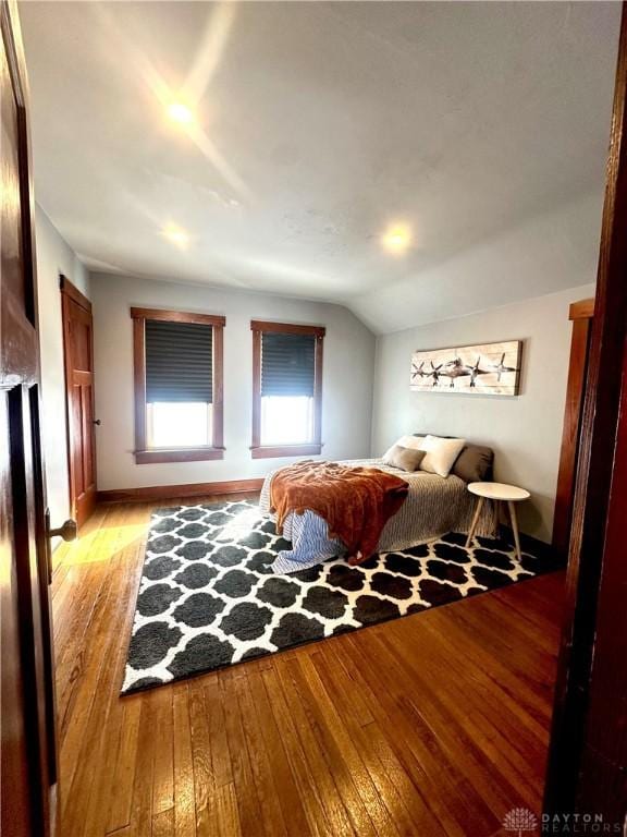 bedroom with baseboards, lofted ceiling, and light wood-style flooring