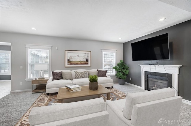 living room with recessed lighting, baseboards, light colored carpet, and a glass covered fireplace